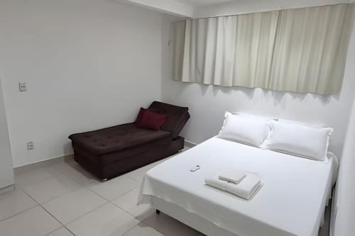 een slaapkamer met een wit bed en een bank bij Apartamento Brisa do Mar in Natal
