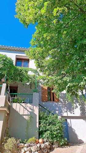 a house with a fence and a tree in front of it at Maison Pivoines in Saint-Martin-dʼArdèche