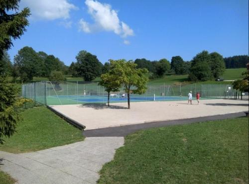 two people playing tennis in a tennis court at Studio cosy à Métabief in Métabief