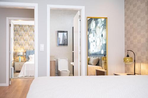a white bedroom with a bed and a bathroom at Casa Graminho in Ponta do Sol