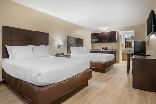 a hotel room with two beds and a kitchen at SureStay Studio by Best Western Gonzales in Gonzales