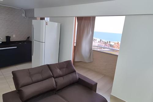 a living room with a couch and a refrigerator at Apartamento brisa do oceano in Natal