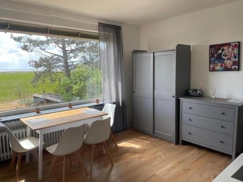 a dining room with a table and chairs and a window at Ferienwohnung-Neuwerk in Baltrum