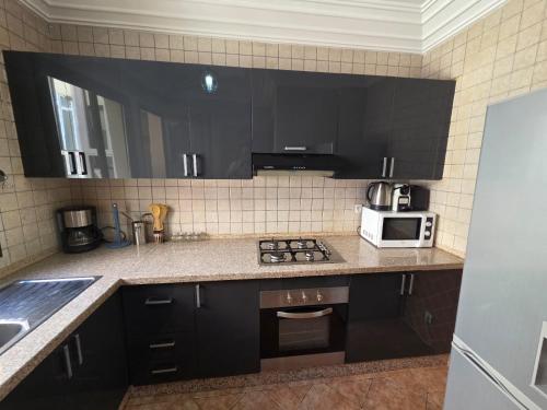 a kitchen with black cabinets and a white microwave at andlous 4 in Marrakech