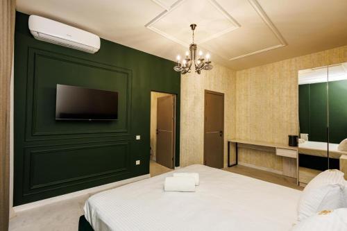 a bedroom with a green wall with a tv and a bed at New York Hotel Yerevan in Yerevan