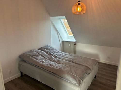 a bed in a room with a light and a window at 11F 2 TV Højbanetorvet in Vejle