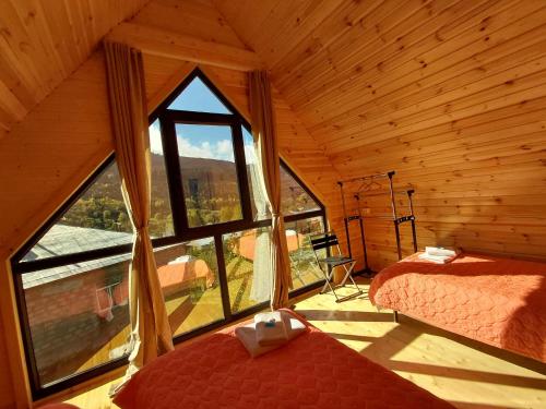 a room with two beds and a large window at Hilltop cottage Mestia in Mestia