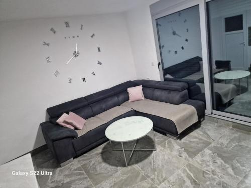 Una sala de estar con un sofá y un reloj en la pared. en Apartmani Kruče, en Ulcinj