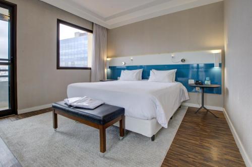 Un dormitorio con una gran cama blanca y una mesa. en Quality Faria Lima, en São Paulo