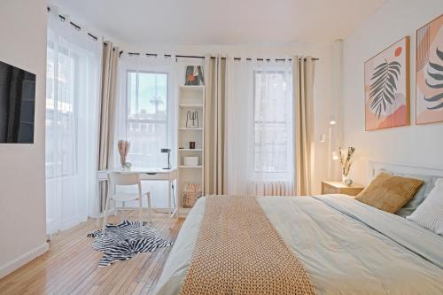 a white bedroom with a large bed and a desk at Warm and Welcoming 2BR in Upper East Side in New York