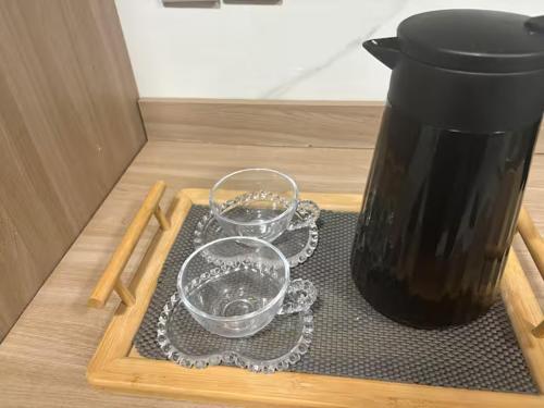 a tray with two glasses on a table with a vase at Estadia Incrível Aconchego e Praticidade Juntas in Lucas do Rio Verde