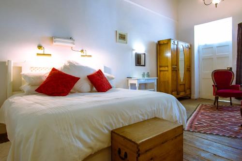 a bedroom with a large white bed with red pillows at The Barracks in Colesberg