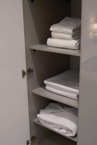 ein Schrank voller weißer Handtücher und ein Stapel Handtücher in der Unterkunft Tashkent City Downtown Deluxe Host Apartments in Taschkent