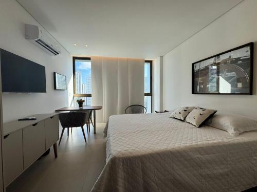 a bedroom with a bed and a desk and a table at Flat em Boa Viagem - Edifício Rooftop 470 in Recife