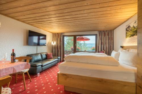 um quarto de hotel com uma cama grande e um sofá em Berghof Mehlan em Fischen