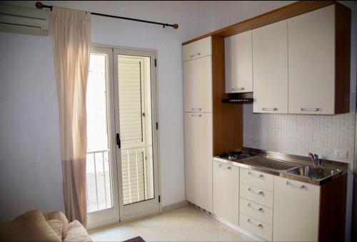 a kitchen with white cabinets and a sink and a window at Almarea Scoglitti in Vittoria