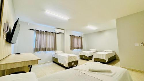 une salle d'hôpital avec trois lits et une télévision dans l'établissement GRAN PARADA HOTEL, à Castanhal
