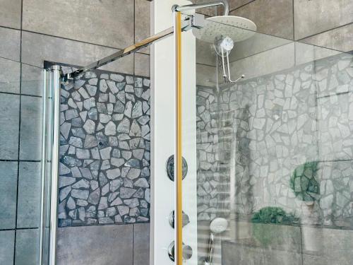 a shower in a bathroom with a stone wall at Dom nad jeziorem Miedwie, Zieleniewo in Zieleniewo