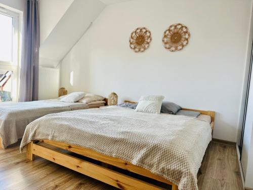 two beds in a bedroom with white walls and wooden floors at Dom nad jeziorem Miedwie, Zieleniewo in Zieleniewo
