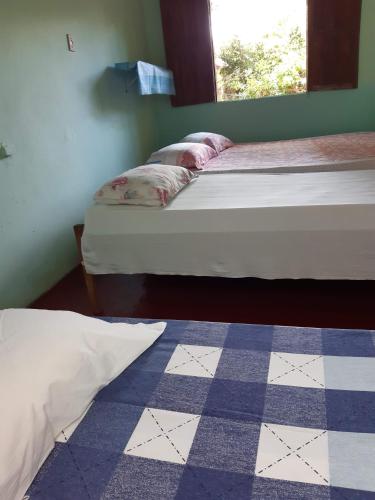 two beds in a room with a checkered floor at Chalé Rústico Cumuruxatiba in Cumuruxatiba