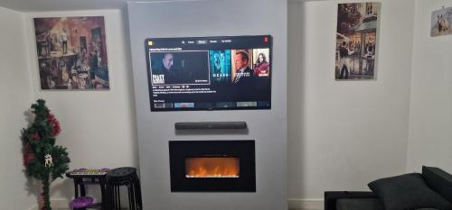 a living room with a fireplace with a tv on it at Solid Mirror Home Milton Keynes in Bletchley