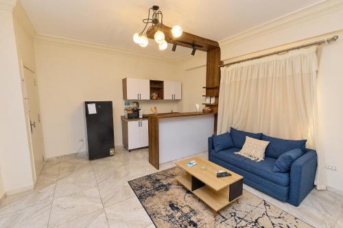 Una sala de estar con un sofá azul y una mesa. en Settle Inn South 90 Apartments, en El Cairo