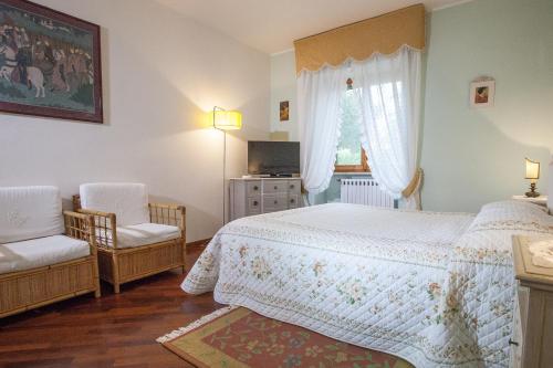 a bedroom with a bed and two chairs and a television at AL MANDORLO Casa Vacanze in Viterbo