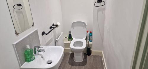 een kleine badkamer met toilet en wastafel bij Solid Mirror Home Milton Keynes in Bletchley