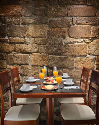 einem Holztisch mit Stühlen und Gläsern Orangensaft in der Unterkunft H10 Raco del Pi in Barcelona