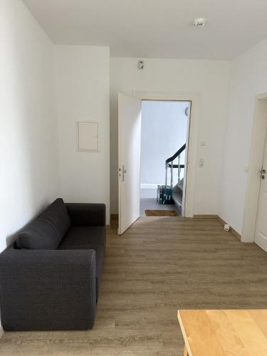 a living room with a black couch and a hallway at Wupper Apartments Vogel in Erbschlö