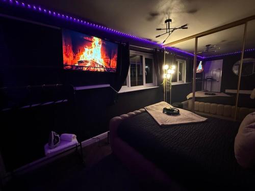 a dark room with a bed and a tv at A Star Living in Liversedge