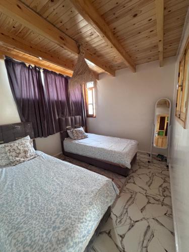 two beds in a room with wooden ceilings at Rooftop apartments in Taghazout