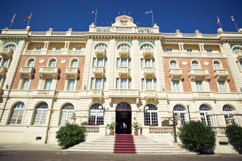 a building with a red staircase in front of it at Grand Hotel Cesenatico in Cesenatico