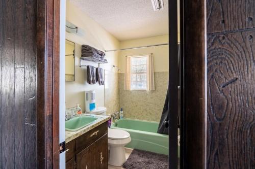 bagno con vasca verde, servizi igienici e lavandino di LaRue's Private Lakeside Cottage ad Abbeville