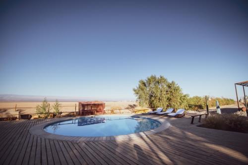 a swimming pool on a wooden deck with chairs around it at Espacio El Sol in La Tirana