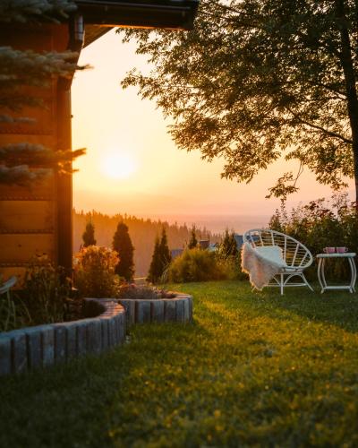 a chair sitting on a lawn with the sunset in the background at Willa Paula - Jacuzzi, Sauna & Grill in Ząb