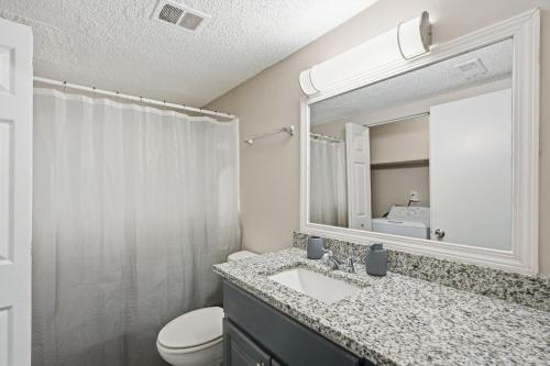 Un baño con lavabo, inodoro y espejo. en Crest At East Cobb 1828d Serene 2bd 15bt, en Marietta