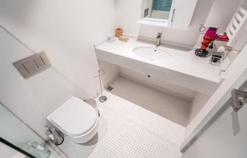 a white bathroom with a toilet and a sink at New Gudauri Atrium in Gudauri