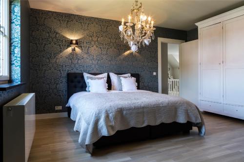 a bedroom with a large bed with a chandelier at B&B Vinedo in Zele