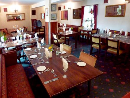 una sala da pranzo con un grande tavolo in legno in un ristorante di The Douglas Hotel a Langholm
