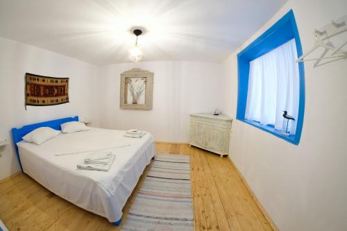 a bedroom with a white bed and a blue window at La Lipoveni in Jurilovca