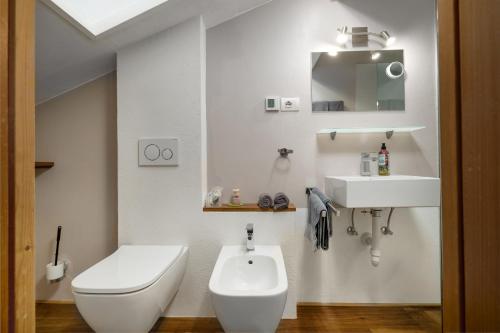 a white bathroom with a toilet and a sink at Haus Lasaun in Bressanone
