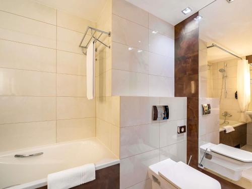 a bathroom with a tub and a toilet and a sink at Mercure Karpacz Skalny in Karpacz