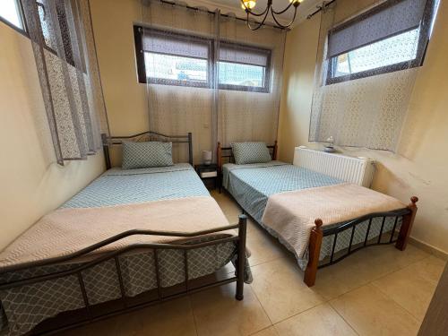 two beds in a room with two windows at Fotini's Holiday Beach Home in Dhíkella