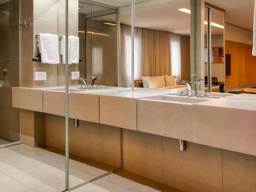 a bathroom with two sinks and a mirror at Mercure Belo Horizonte Vila da Serra in Belo Horizonte