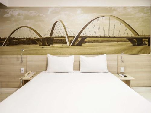 a large bed with a painting of a bridge at Mercure Brasilia Lider in Brasilia