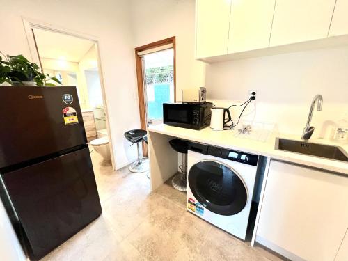 a kitchen with a black refrigerator and a microwave at Cosy Retreat Near Mairangi Bay in Auckland