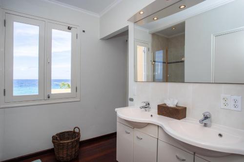 une salle de bain blanche avec un lavabo et un miroir dans l'établissement Oceanfront Colonial Villa with Pool, à Willemstad