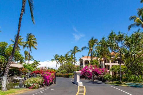 een huis in een straat met palmbomen en bloemen bij Golf Course Townhome in Waikoloa Beach in Waikoloa