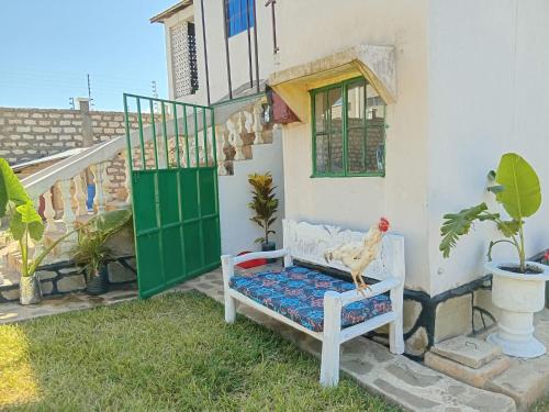 a chicken sitting on a bench in front of a house at Tango house in Ukunda